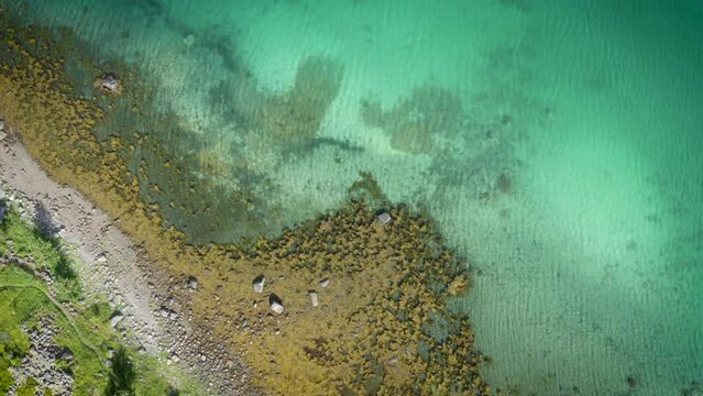 Drone flying over the beautiful coastal line with turquoise sea water near Henningsvaer in Lofoten, Norway