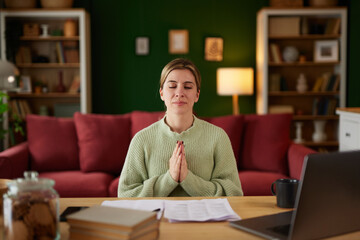 Calm woman meditating to reduce stress working on computer at home office