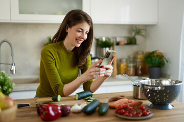 Woman cooking at home following an online recipe on mobile phone