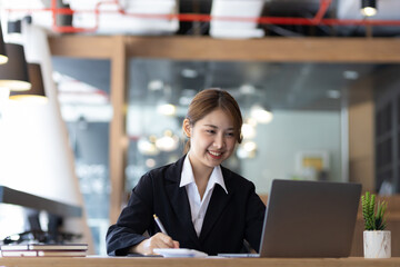 Attractive Asian businesswoman in the office working with financial documents on the desk.