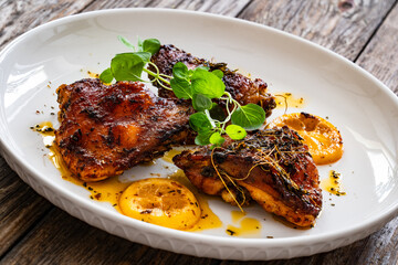Roasted chicken thighs with lemon on wooden table
