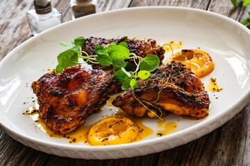 Roasted chicken thighs with lemon on wooden table
