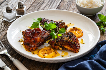 Roasted chicken thighs with lemon on wooden table
