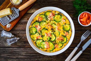 Omelette - scrambled eggs with smoked salmon and zucchini on wooden table