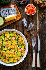 Omelette - scrambled eggs with smoked salmon and zucchini on wooden table