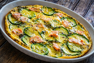 Omelette - scrambled eggs with smoked salmon and zucchini on wooden table