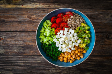 Fresh vegetable salad with feta cheese on wooden table
