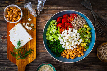 Fresh vegetable salad with feta cheese on wooden table
