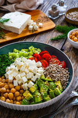 Fresh vegetable salad with feta cheese on wooden table
