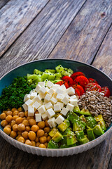 Fresh vegetable salad with feta cheese on wooden table

