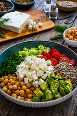 Fresh vegetable salad with feta cheese on wooden table
