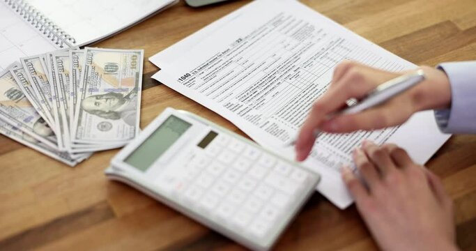 Business woman filling out tax form 1040 and counting on calculator. Registration of financial documents and tax time