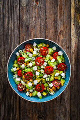 Fresh vegetable salad with feta cheese on wooden table
