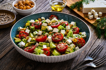 Fresh vegetable salad with feta cheese on wooden table
