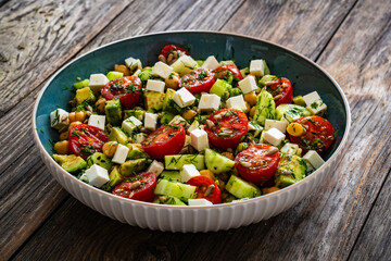 Fresh vegetable salad with feta cheese on wooden table
