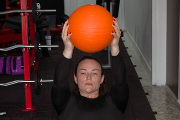 sporty woman doing exercises with a heavy ball in a gym