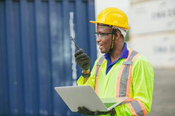 African male dock worker control loading containers cargo at warehouse container shipyard. Marine and carrier staff employee. cargo loading operator shipping export logistics ship yard.