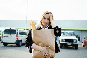 A sad woman holding a paper bag outside the grocery store