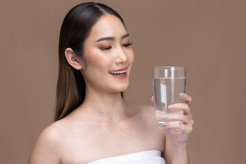 Young Asian woman holding glass of water on beige  cream background.Beauty portrait of charm lifestyle healthy and  beauty woman.