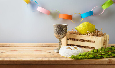 Jewish holiday Sukkot concept with traditional symbols and decorations on wooden table over gray...