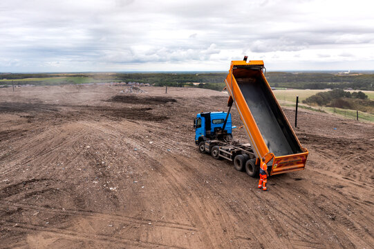 Aerial view of a tipper truck with raised trailer on a landfill site