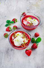 Traditionelle gefrorene Erdbeersuppe mit Vanilleeis und gehackte Pistazien serviert als Draufsicht auf einem Design Board mit Textfreiraum