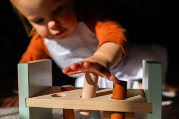 Toddler child playing with hammer pounding bench toy using hands to press blocks