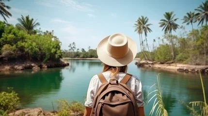 Foto op Canvas Traveling lady with rucksack and straw cap looking at tropical waterway at sunny day © Roma