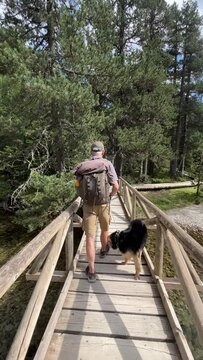 Man hiking with his dog in summer in a high mountain forest near a river. Friendship, and loyalty concepts. 