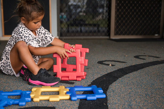 Young Aboriginal girl playing at preschool with plastic toy