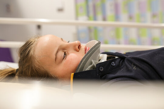 Young girl wearing neck brace in hospital bed