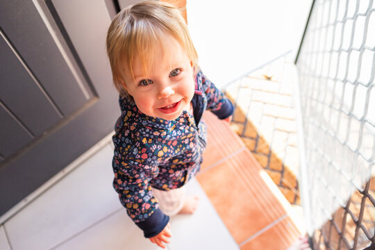 Toddler girl by front door step of house waiting to go outside for a walk with parent