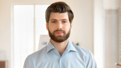 Close up headshot portrait of serious Caucasian male employee look at camera pose in office,...