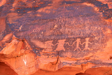 Close up view of Native American rock art (Petroglyphs) on red Aztek sandstone wall in Petroglyph Canyon along Mouse Tank hiking trail in Valley of Fire State Park in Mojave desert, Nevada, USA