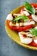 Yellow Plate of Healthy Classic Caprese Salad with Mozzarella Cheese, Tomatoes and Basil. Italian Cuisine