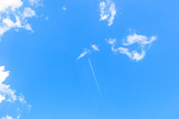 Commercial airplane in blue sky between light cirrus clouds