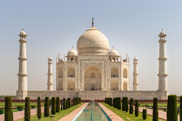 Fototapeta na wymiar A majestic Tajmahal, one of the world's seven wonders is viewed along with its lush green garden. A clear blue sky adds magnificence to the white marble of the beautiful architectural structure.