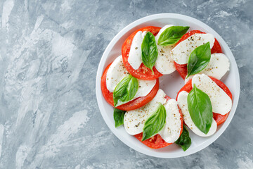 Caprese Salad on white plate. Italian traditional salad caprese on concrete. Copy space