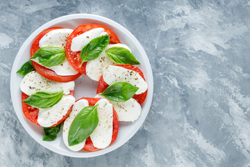 Caprese Salad on white plate. Italian traditional salad caprese on concrete. Copy space