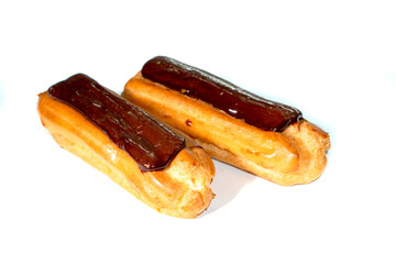 Tasty eclairs covered with chocolate on white background