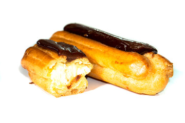 Tasty eclairs covered with chocolate on white background