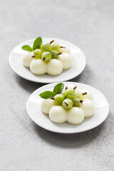 Vegan Gooseberry cream dessert, Panna Cotta in the shape of truffles, decorated with fresh gooseberries. On a plate. Light grey background
