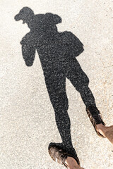 Legs and the shadow of a person on the asphalt