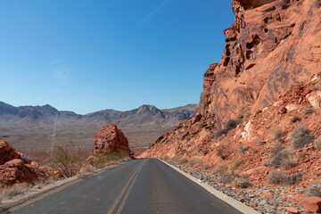 Panoramic view of endless winding empty Mouse tank road in Valley of Fire State Park through canyons of red Aztec Sandstone Rock formations and desert vegetation in Mojave desert, Overton, Nevada, USA