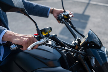 Caucasian man rides an electric motorcycle. Close-up of male hands on the steering wheel. 