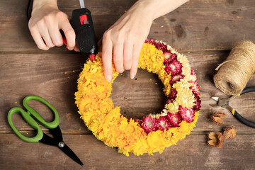 Florist at work: woman shows how to make a door wreath with dry flowers and orher plants. Step by step, tutorial.