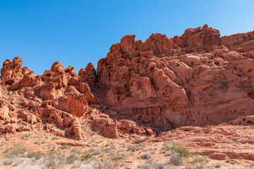 Fototapeta premium Exterior view of windstone arch and fire cave in Valley of Fire State Park, Mojave desert, Nevada, USA. Scenic view of beehive shaped red sandstone rock formations. Barren deserted landscape in summer
