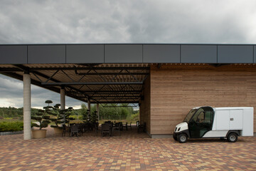 Empty summer cafe patio on the open terrace. An electric car near a cafe at a gas station.