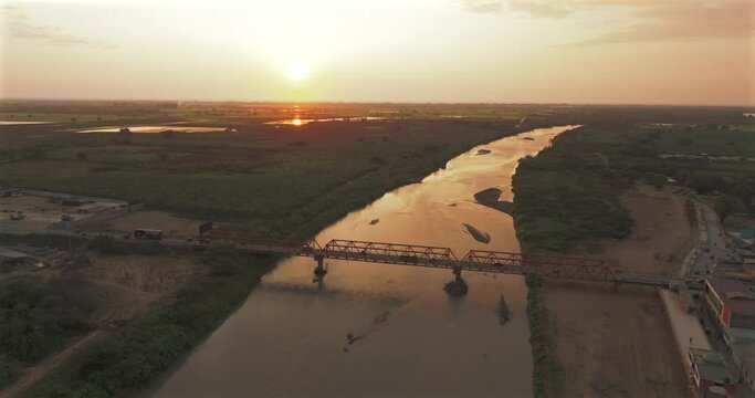 Aerial shot of Tumbes river, bridge and city at sunset. Tropical city at north of Per&uacute;. 