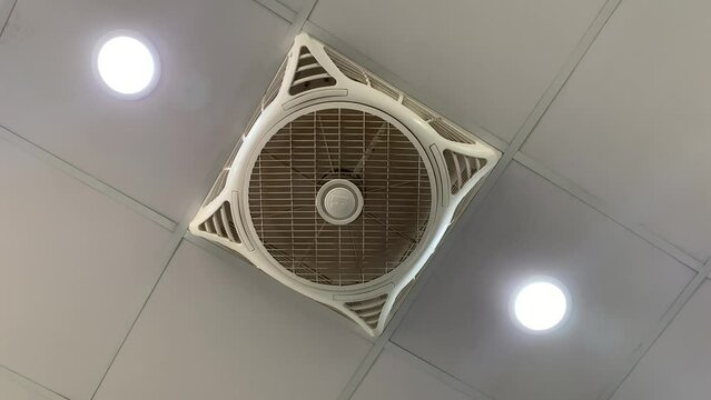 Ceiling fan rotating at high speed, electric fan is spinning around.